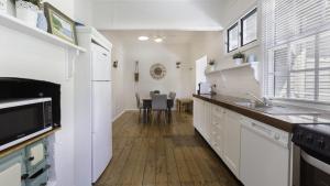 eine Küche mit weißen Schränken und einem Tisch mit Stühlen in der Unterkunft 'Wagstaffe Cottage' by HolidayCo in Booker Bay