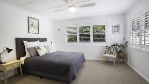 ein Schlafzimmer mit einem Bett und einem Stuhl und Fenstern in der Unterkunft 'Wagstaffe Cottage' by HolidayCo in Booker Bay + 9 Fotos