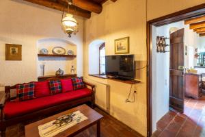 a living room with a red couch and a tv at Ilianthos Traditional Maisonette in Hersonissos