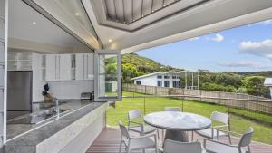a kitchen and dining area with a table and chairs at 'A Beachside Getaway - 8' by HolidayCo in Killcare