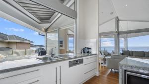 a kitchen with a view of the ocean at 'A Beachside Getaway - 8' by HolidayCo in Killcare