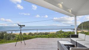 a camera on a tripod with a view of the ocean at 'A Beachside Getaway - 8' by HolidayCo in Killcare