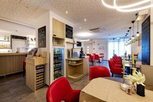 INSIDE Hotel Nordhorn في نوتهورن: متجر للنبيذ وكراسي حمراء وطاولة في الغرفة