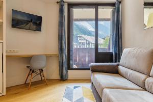 ein Wohnzimmer mit einem Sofa und einem großen Fenster in der Unterkunft Chamonix Sud - Lognan 106 - Happy Rentals in Chamonix-Mont-Blanc