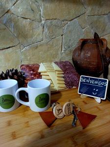 een tafel met twee koffiekopjes en een bos kaas bij El Pico de Aroche in Cortegana