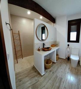 een badkamer met een wastafel, een toilet en een spiegel bij El Pico de Aroche in Cortegana
