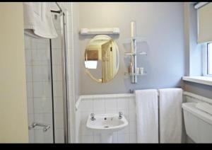 ein weißes Badezimmer mit einem Waschbecken und einem Spiegel in der Unterkunft Almara House in Galway