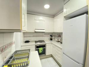 eine weiße Küche mit einem Herd und einem Kühlschrank in der Unterkunft Flor Habitaciones in Barcelona