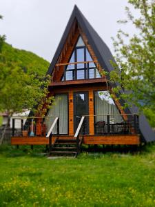 una pequeña casa con techo negro en un campo verde en B&B Cottage in Mestia en Mestia