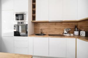 een witte keuken met witte kasten en een spoelbak bij "Golden Sky"Rooftop Pool Villa in Vodice