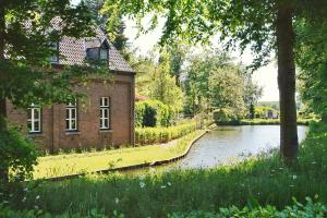 a brick building next to a river next to a house at Het Knechthuys in Baarlo