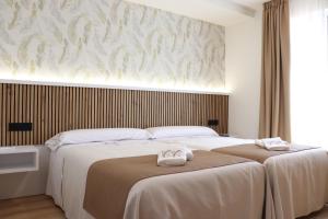 two beds in a bedroom with two towels on them at Apartamento Casa Cruceiro in Arzúa