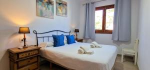 ein Schlafzimmer mit einem Bett mit blauen Kissen und einem Fenster in der Unterkunft Villa con jardin cerca de la playa in Muro