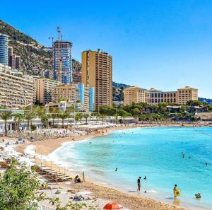 a beach with people in the water and buildings at 1 meter from Monaco. 5 min by elevators to Larvotto beach. in Beausoleil