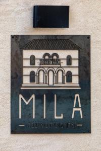 um sinal para um edifício ao lado de uma parede em Mila - Boutique Hotel em Haifa