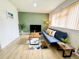 a living room with a blue couch and a table at KozyGuru Spacious 3 BR 8ppl Hse 50% off Long stay in Manchester