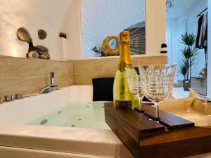 - une salle de bains avec baignoire, bouteille de champagne et verres dans l'établissement Le Petit Bijou di Dolceacqua, per un momento romantico, à Dolceacqua