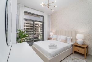 a white bedroom with a bed and a window at Nasma Luxury Stays - Laya Heights in Dubai