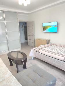 1 dormitorio con cama, mesa y TV en Современная квартира с видом на горы en Almaty