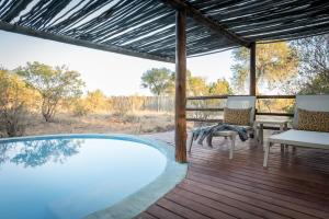 einen Pool auf einer Terrasse mit 2 Stühlen und einem Tisch in der Unterkunft Africa on Foot in Klaserie Private Nature Reserve