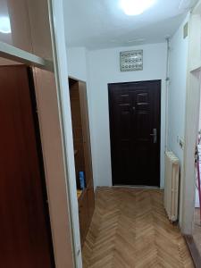 a hallway with a black door and a wooden floor at Stan na dan in Valjevo