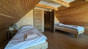 a bedroom with two beds in a wooden cabin at Dom pod Modrzewiem in Świątki