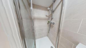 La salle de bains est pourvue d'une douche avec une porte en verre. dans l'établissement Bicester Court Lodge The Langford Room, à Bicester