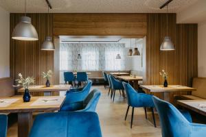 a restaurant with wooden tables and blue chairs at Salzl Seewinkelhof in Illmitz