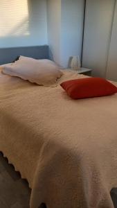 a bed with a red pillow on top of it at Appartement individuel en maison in Beaumont-sur-Oise