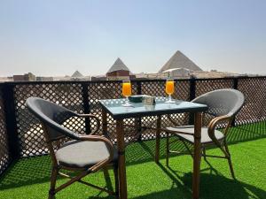 a table with two chairs and two glasses of orange juice at Nefertari pyramids inn in Cairo
