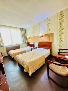 Pokój hotelowy z 2 łóżkami i krzesłem w obiekcie Kharaa Hotel & Restaurant w Ułan Bator