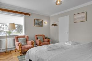 una camera da letto con due sedie e un letto e una finestra di Audur Guesthouse a Reykjavik