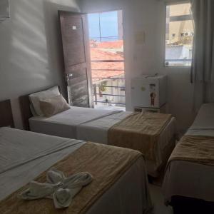 a hotel room with three beds and a window at Jampa Mar Pousada in João Pessoa