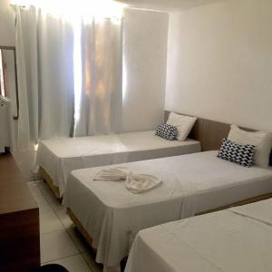 a room with three beds and a window at Jampa Mar Pousada in João Pessoa