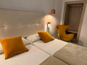 een slaapkamer met een bed met gele kussens en een stoel bij Aparthotel Boutique Poniente Playa in San Antonio