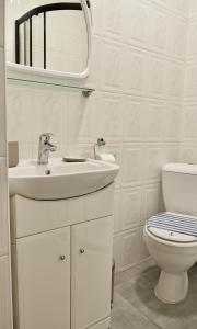 a white bathroom with a sink and a toilet at Bursztynek in Władysławowo