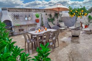 eine Terrasse mit einem Tisch, Stühlen und einem Sonnenschirm in der Unterkunft Casa Grasso in Vittoria