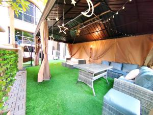 d'une terrasse avec une table, un canapé et une pelouse. dans l'établissement ELAN RIMAL SADAF Suites, à Dubaï