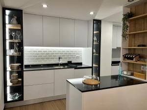 a kitchen with white cabinets and black countertops at Pink House in Monção