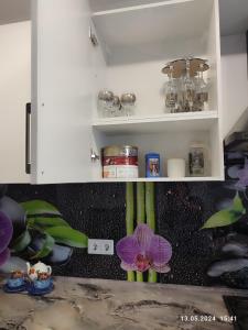 a kitchen with white cabinets and a purple flower at Современная квартира с видом на горы in Almaty