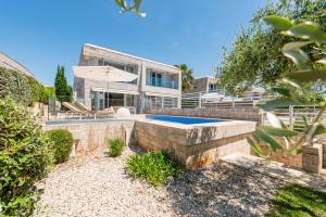 a house with a swimming pool in the backyard at Villa Camelia ZadarVillas in Petrcane