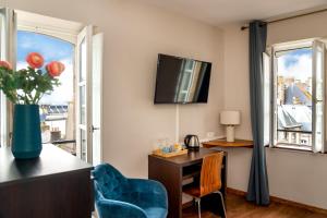 a living room with a desk and a tv on the wall at Hotel Elizabeth - Intra Muros in Saint Malo