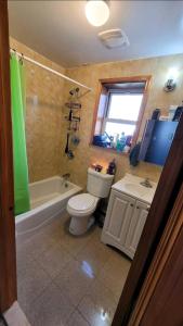 uma casa de banho com um WC, uma banheira e um lavatório. em Comfortable rooms in NYC near the train em Woodside