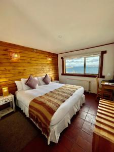 um quarto com uma cama grande e uma janela grande em Weskar Lodge Hotel em Puerto Natales