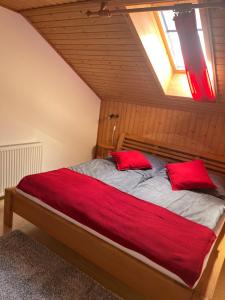 Pferdehof Almgut في فيستينو: غرفة نوم عليها سرير ومخدات حمراء