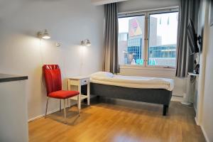 a bedroom with a bed and a chair and a window at Hotelli Kerava in Kerava