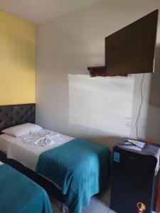 a bedroom with two beds and a flat screen tv at Pousada por do soll in Serra do Cipo