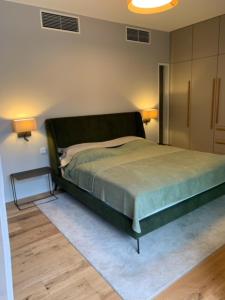 1 dormitorio con 1 cama verde y 2 lámparas en Marina Apartment am See mit Pool und Sauna, en Bad Saarow
