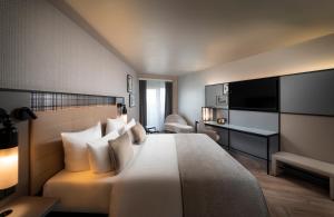 a hotel room with a bed and a television at Leonardo Royal Hotel Frankfurt in Frankfurt/Main