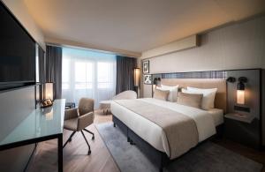 una camera d'albergo con un grande letto e una TV di Leonardo Royal Hotel Frankfurt a Francoforte sul Meno